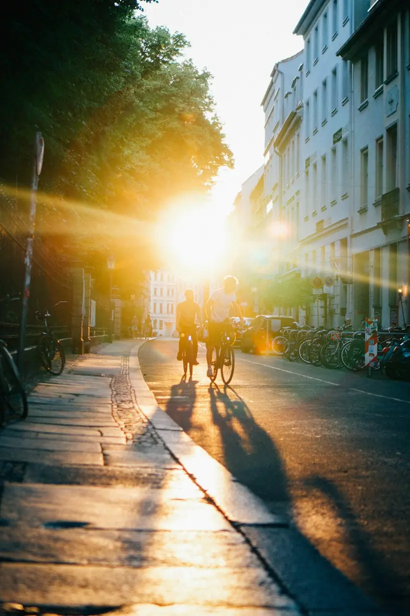 Cyclists riding down a city street at sunrise